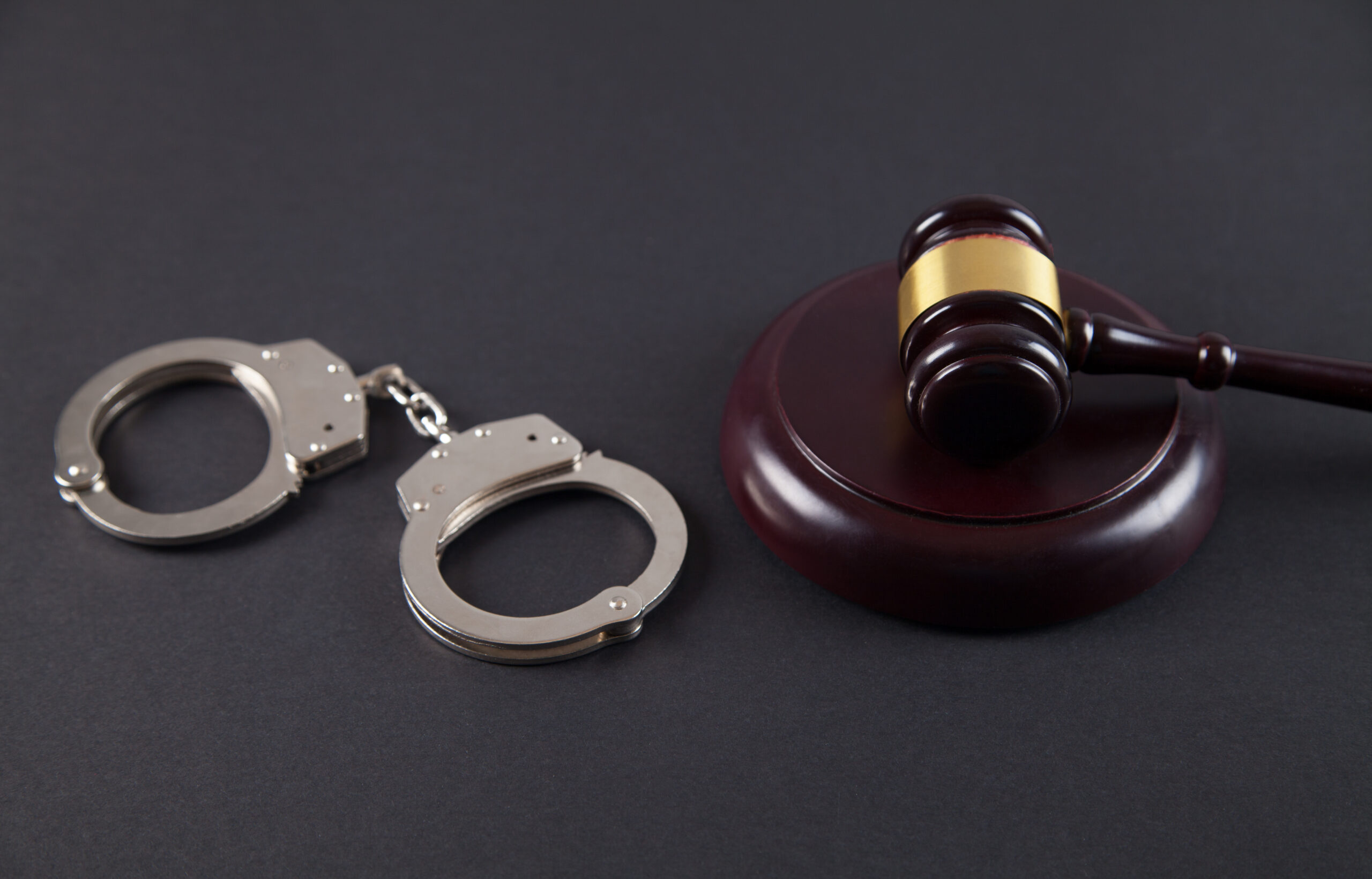 Police,Handcuffs,And,Judge,Gavel,On,An,Isolated,Black,Background.